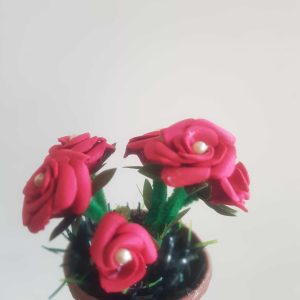 una maceta de rosas rojas con perlas en el centro