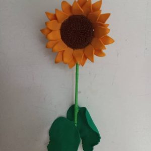 Un girasol de foami con hojas verdes.