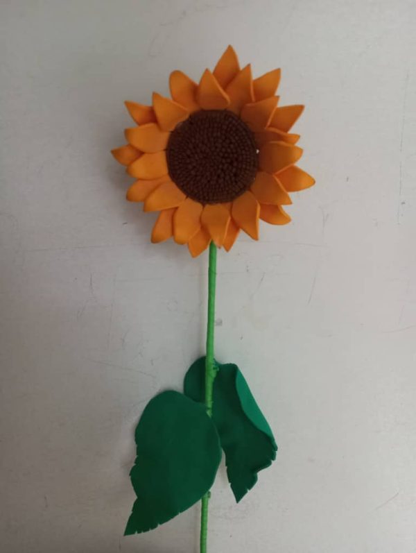 Un girasol de foami con hojas verdes.