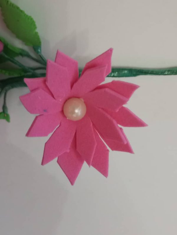 una flor rozada con una perla en el centro